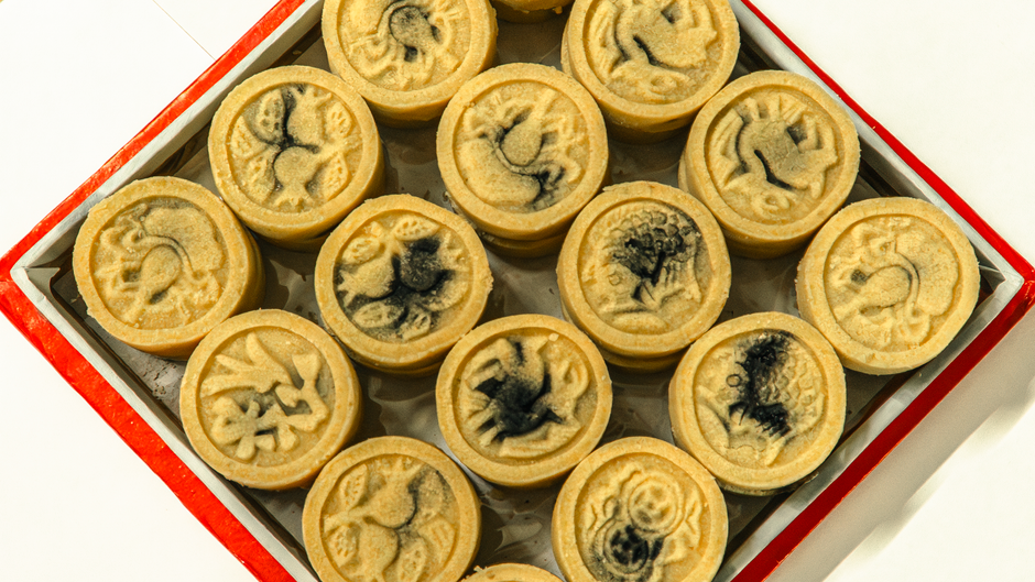 A tray of traditional mooncakes featuring artistic impressions on individual cakes.